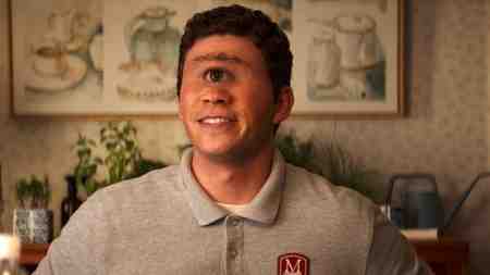 Daniel Diemer as Tyson sitting in a resort lobby in Percy Jackson and the Olympians