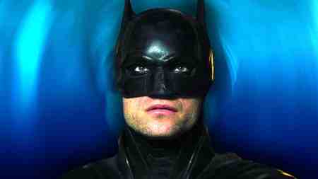 Robert Pattinson as Batman in his mask looking at the screen in The Batman.