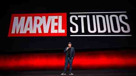 Kevin Feige giving a presentation in front of the Marvel Studios logo.