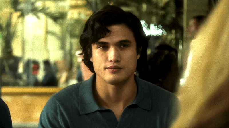 Charles Melton as Joe Yoo sitting at a diner table in May December
