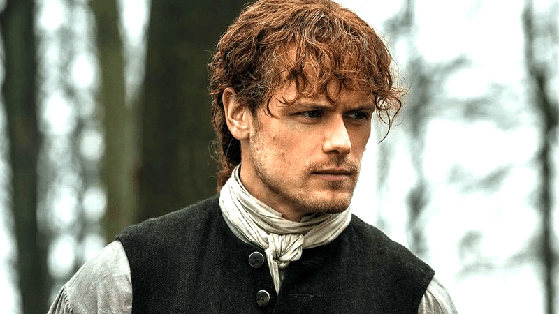 Sam Heughan as Jamie Fraser standing in a forest in Outlander