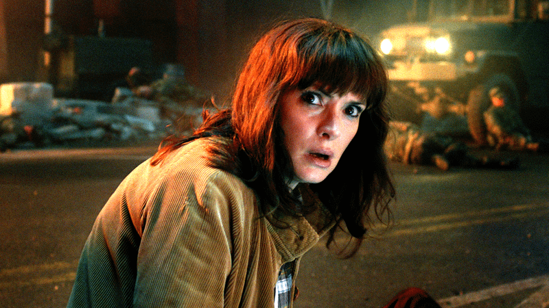 Winona Ryder as Joyce Byers bent down on a city street in Stranger Things 5