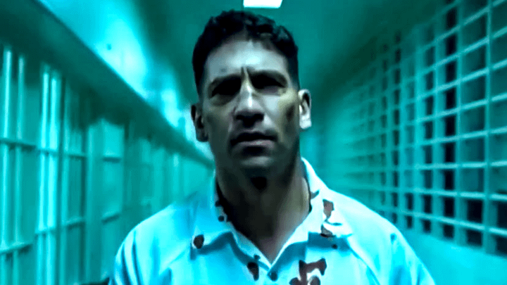 Frank Castle in a prison with blood on his shirt.