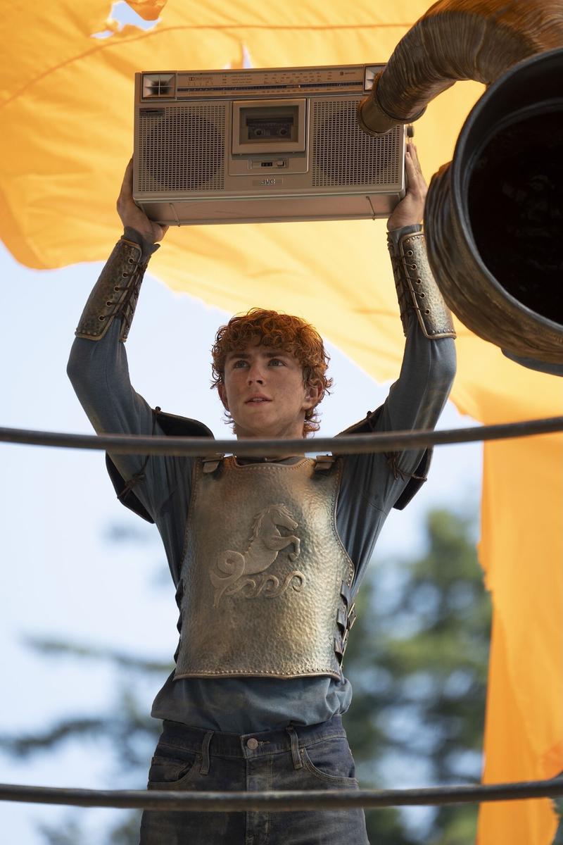 Walker Scobell as Percy Jackson holding a boom box in 