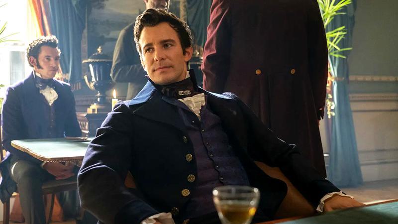 Luke Thompson as Benedict Bridgerton leaning back in a chair in Bridgerton