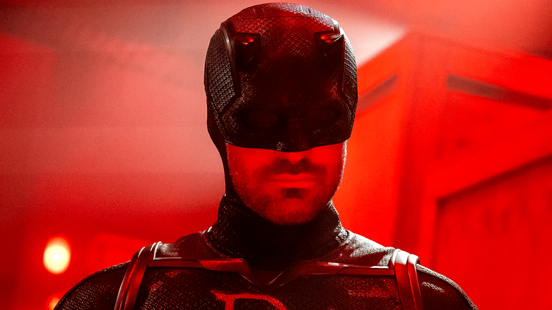 Charlie Cox Daredevil in black suit in red light.