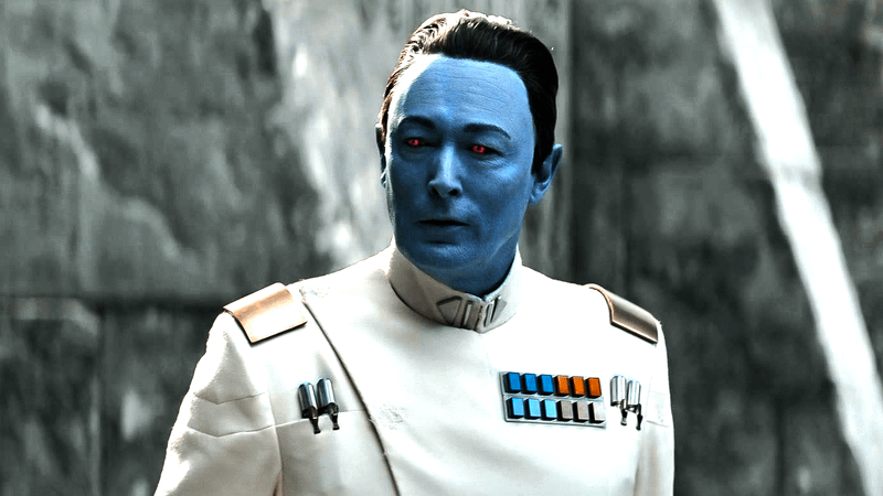 Lars Mikkelsen, as Grand Admiral Thrawn, stands in front of a gray stone wall in Ahsoka Season 1.