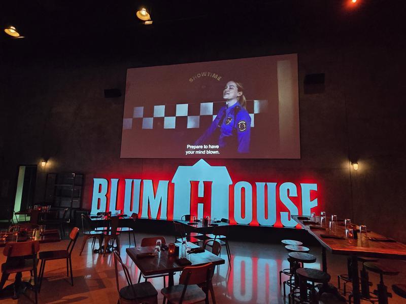 Premiere House with Blumhouse illuminated sign and large screen playing 'Five Nights at Freddy's'.