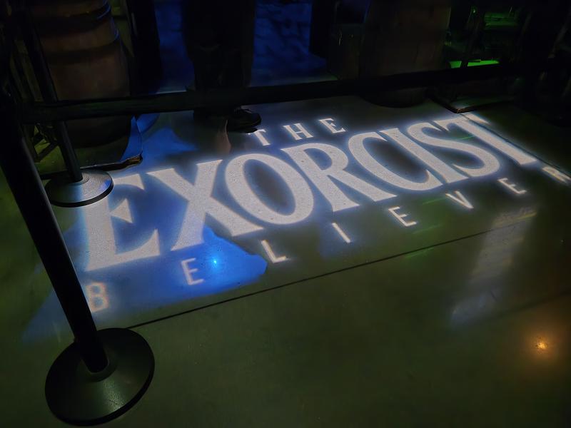 White illuminated text 'The Exorcist Believer' on floor.
