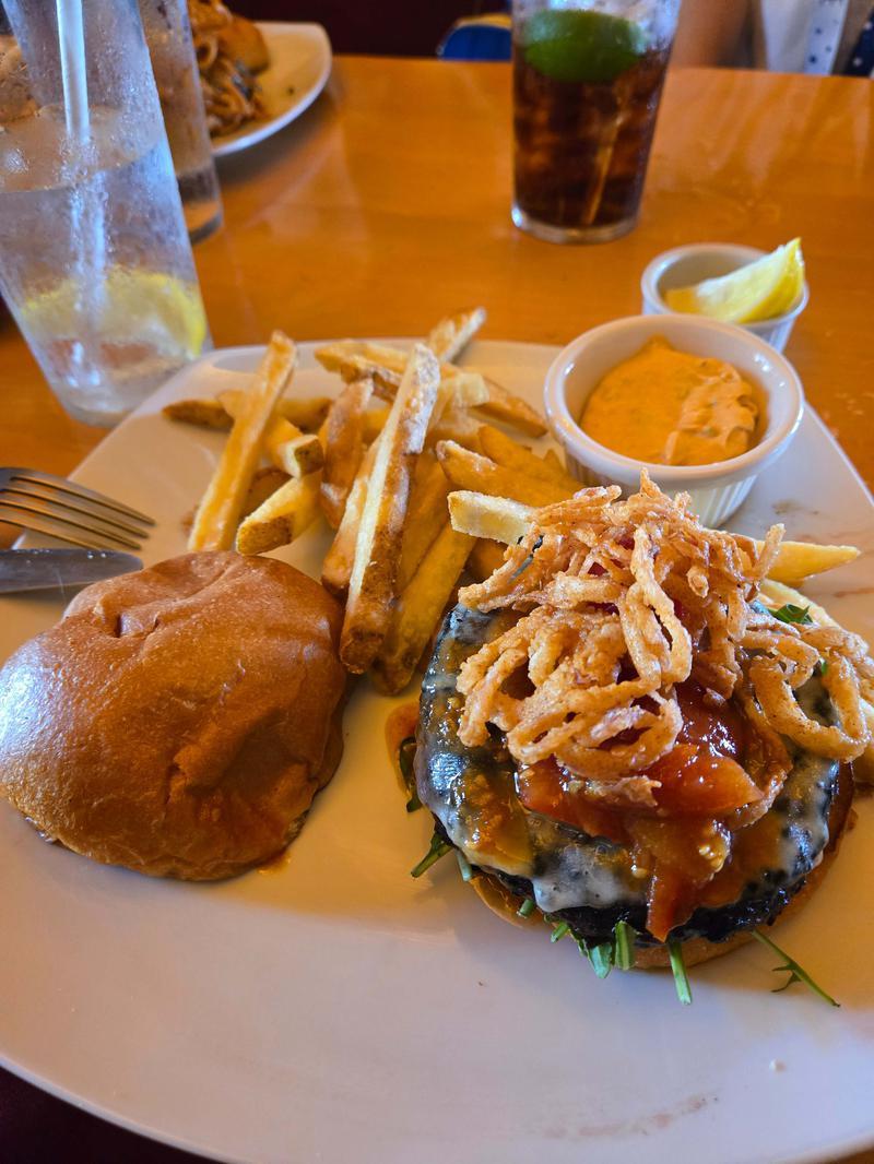 A burger, fries, and cup of honey mustard on a white plate.