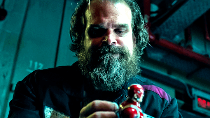 Red Guardian sitting in a prison food hall with a Red Guardian action figure.