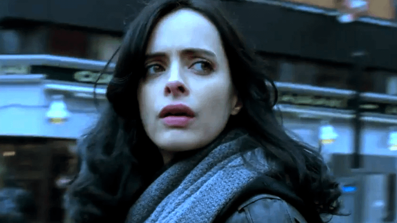 Krysten Ritter as Jessica Jones looking over her shoulder on a city street in Jessica Jones