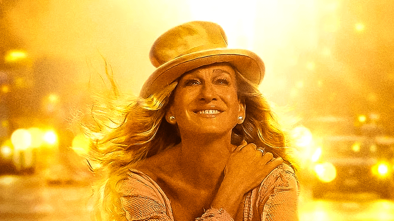 Sarah Jessica Parker as Carrie Bradshaw bathed in gold light in a top hat in And Just Like That...