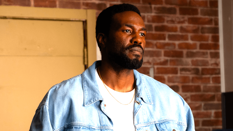 Yahya Abdul-Mateen II as Simon Williams standing in a denim jacket in Wonder Man