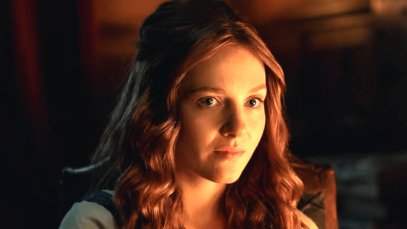 Harriet Slater as Ellen MacKenzie sitting by a fire in Outlander: Blood of my Blood