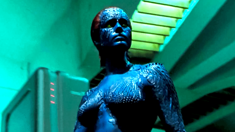 Rebecca Romijn as Mystique in her blue form standing in a lab in X-Men.