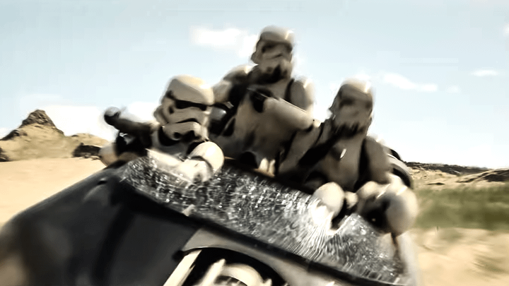 Three stormtroopers riding in a speeder.