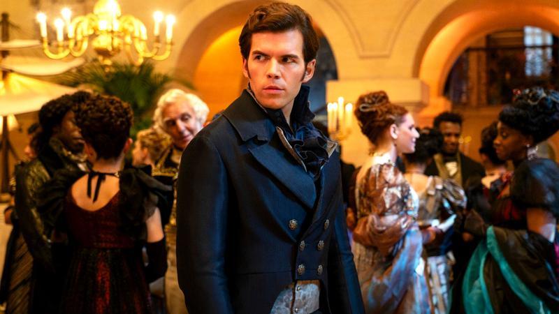 Luke Newton as Colin Bridgerton at a ball looking over his shoulder in Bridgerton