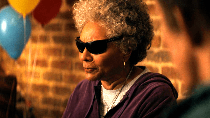 Leslie Uggams as Blind Al in Deadpool & Wolverine wearing glasses and standing in front of balloons.