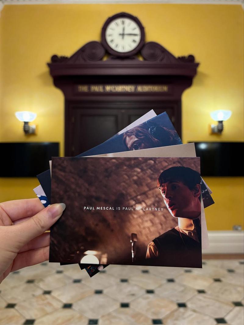 A hand holding some post cards for The Beatles movie.