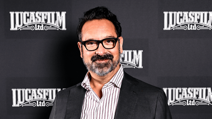 James Mangold in front of gray background drop with Lucasfilm Ltd. logo on it.