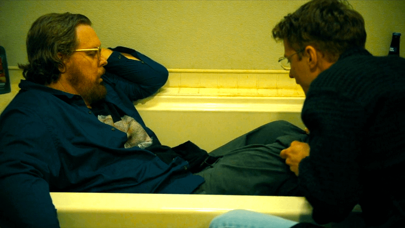 Steve Agee as Economos passed out in a bath tub as Freddie Stroma pulls his pants down in Peacemaker