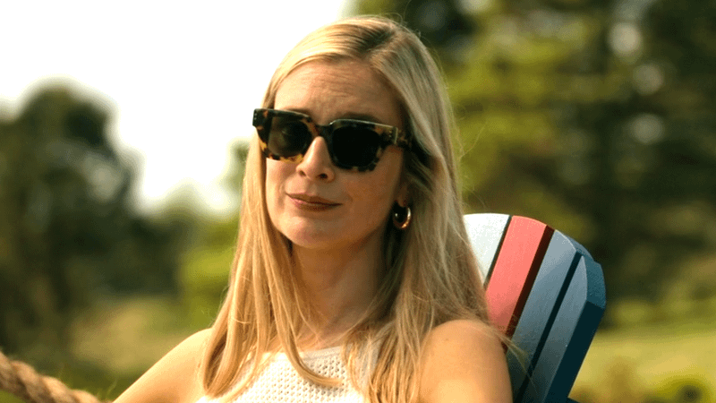 Caitlin FitzGerald as Penny Sinclair sitting in a beach chair in sunglasses in We Were Liars