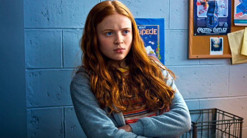 Sadie Sink as Max crossing her arms in a blue sweater in Stranger Things