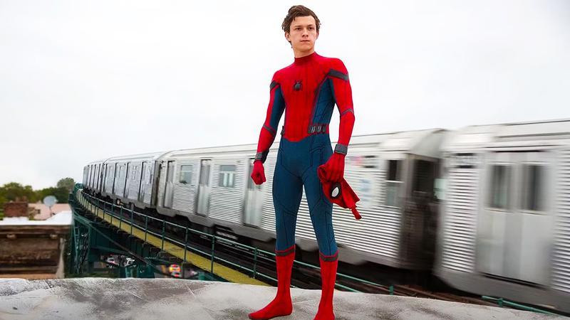 Tom Holland as Spider-Man with his mask off standing on a train in Spider-Man: Homecoming