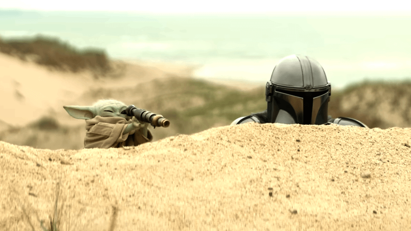 Pedro Pascal as Din Djarin looking over a mound with Grogu at his side in The Mandalorian
