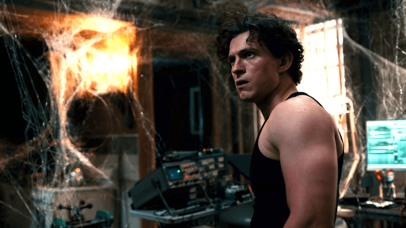 Peter Parker in a black tank-top in an apartment covered in webs.