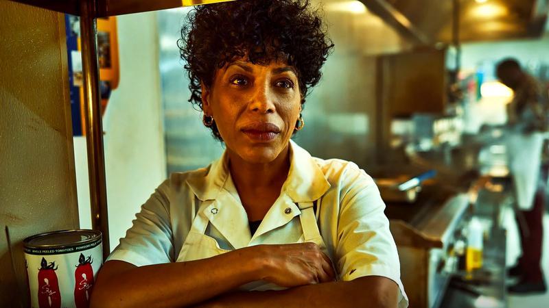 Liza Colón-Zayas as Tina leaning on a counter in The Bear