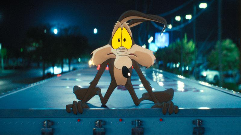 Wile E. Coyote hanging on to the top of a truck.