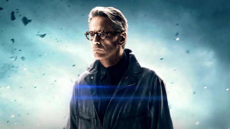 Jeremy Irons as Alfred Pennyworth standing in with glasses on and a open jacket in Batman v Superman