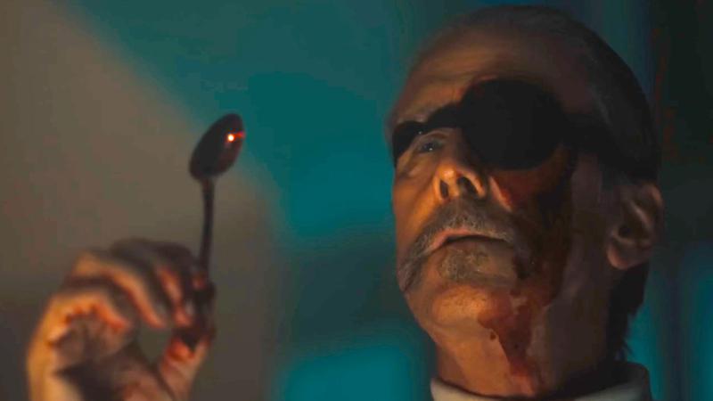 Alan Ruck's Arthur Scott holding a bloody spoon in Corporate Retreat.