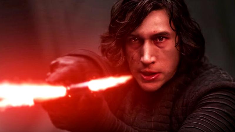Adam Driver as Kylo Ren holding out his red lightsaber in The Force Awakens