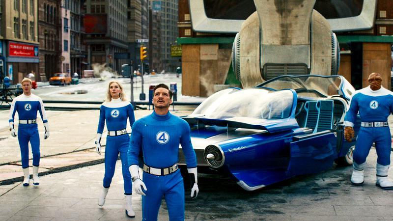 The cast of Fantastic Four: First Steps standing around the Fantasticar on a New York City street looking up at something
