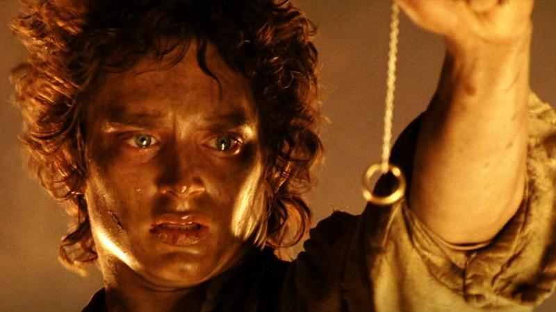 Elijah Wood as Frodo looking at a ring on the end of chain in The Lord of the Rings