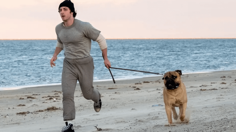 I Play Rocky actor with dog on beach.