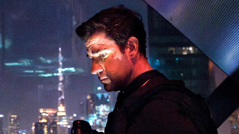 Jack Ryan staring through a window out at the city below him.