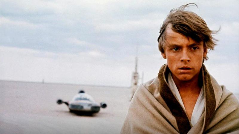 Mark Hamill as Luke Skywalker standing on a desert planet in Star Wars