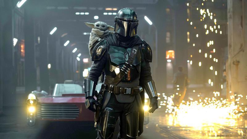 The Mandalorian and Grogu in the self-titled film in front of a small explosion.
