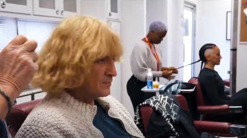 Nathan Fillion wearing a blond wig as Guy Gardner in a makeup chair in Superman