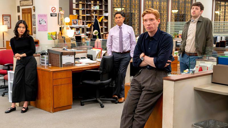 Ned leaning against a desk in the office in The Paper.