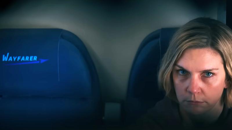 Rhea Seehorn as Carol sitting in a plane seat in Pluribus