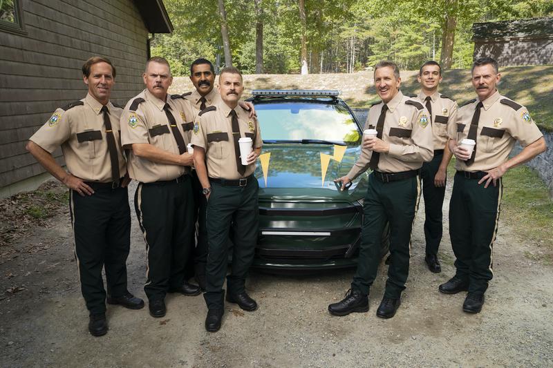 The Super Troopers standing by their new electric car in Super Troopers 3.