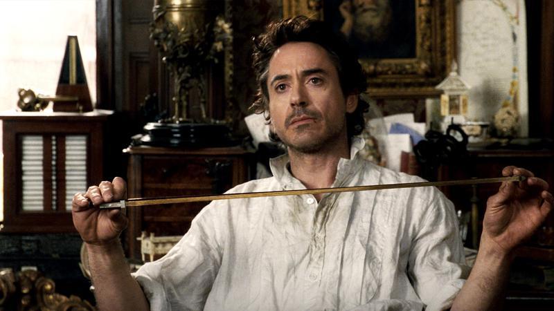 Robert Downey Jr. as Sherlock Holmes holding a measuring tape in Sherlock Holmes