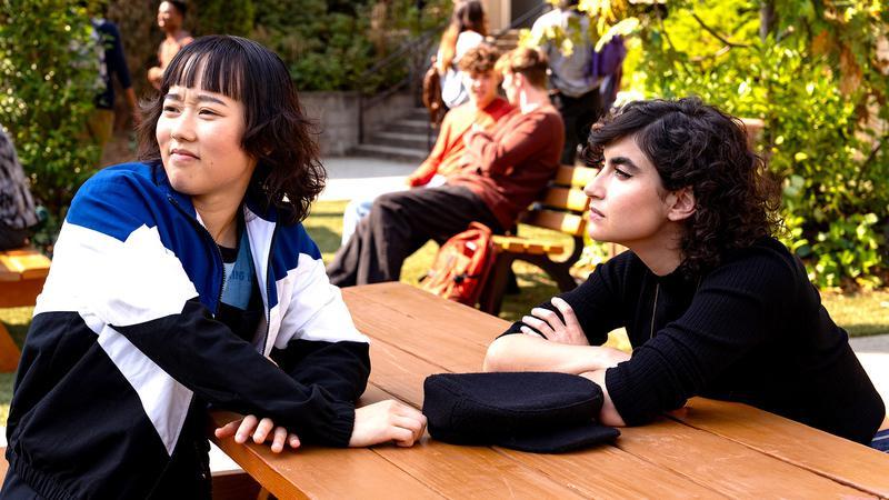 Quinn and Rhonda sitting at a table outside in School Spirits Season 3.