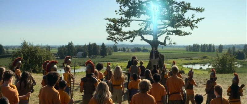 Tyson stands with a glowing trident over his head, while other campers look at him, in 