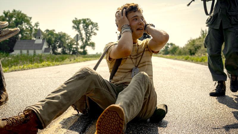 A cast member of The Long Walk holding their head in distress.